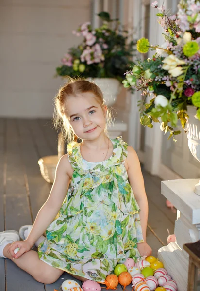 Маленька чарівна дівчинка з кісками в зеленій сукні сидить на т — стокове фото