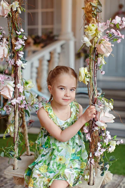 Linda niña en un vestido verde sentado en columpios decorados wi — Foto de Stock