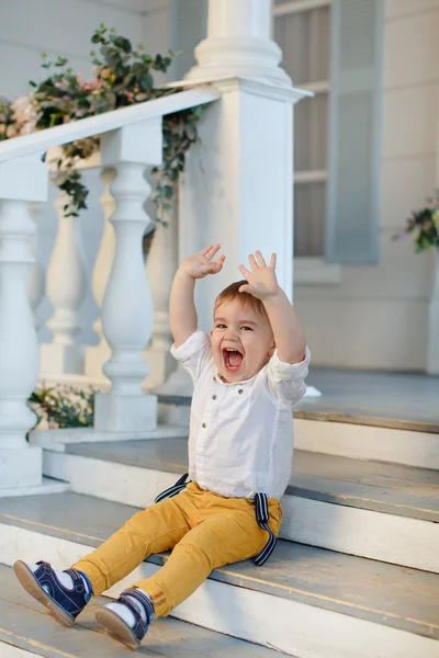 Small charming boy sits on the stairs and shouted, raising his a — Stock Photo, Image