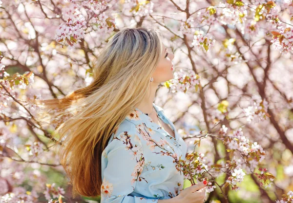 Vacker blond tjej med långt hår i en blå klänning på en bakgrunds — Stockfoto
