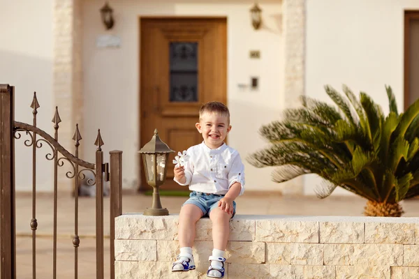 Beyaz gömlekli küçük bir erkek bebek arka planda oturuyor. — Stok fotoğraf