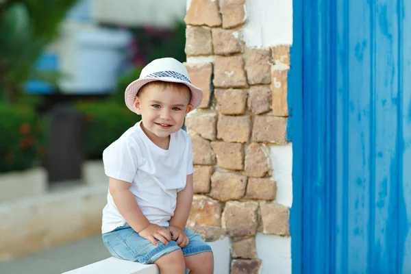 Niño pequeño con sombrero sentado en la casa en verano y sonriente —  Fotos de Stock