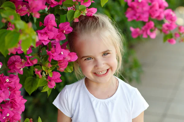 Fata blond fermecător râzând în fundalul de flori roz i — Fotografie, imagine de stoc