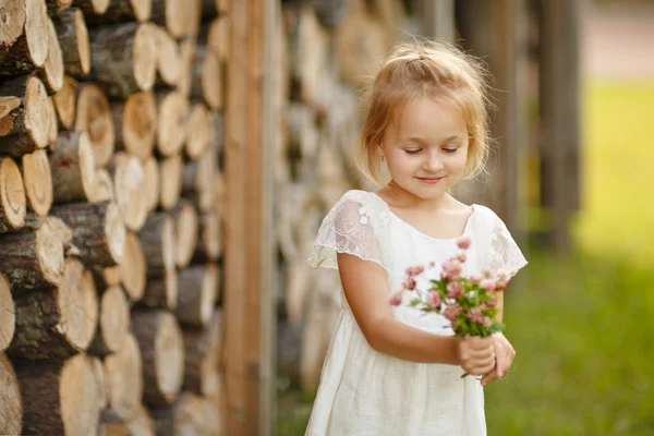 Fetiță 5 ani blondă pe un fundal de lemn, ținând — Fotografie, imagine de stoc