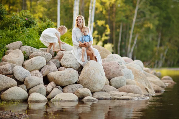 Maman dans une robe blanche avec son fils et sa fille assis sur grand — Photo