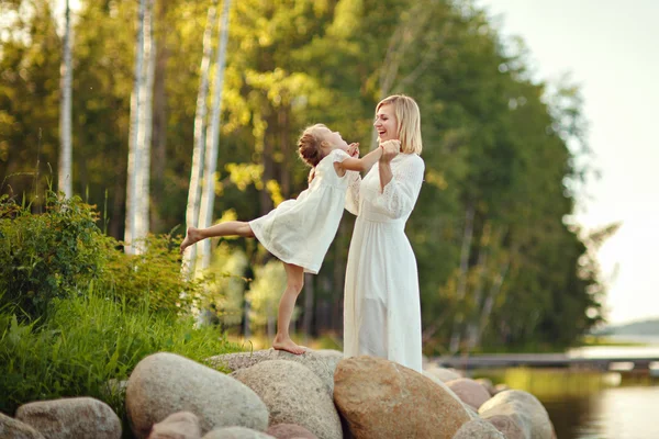 Mutter im weißen Kleid mit ihrer Tochter auf großen Felsen sitzend auf — Stockfoto