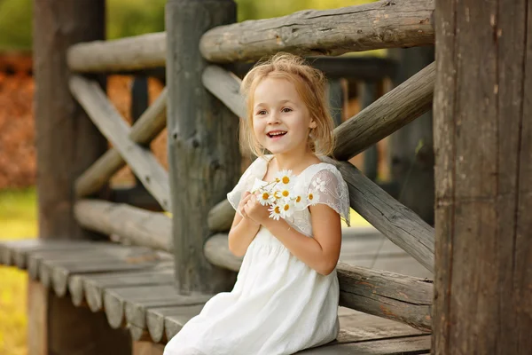 Liten flicka 5 år blonda sittande på en stock hem, hand i hand — Stockfoto