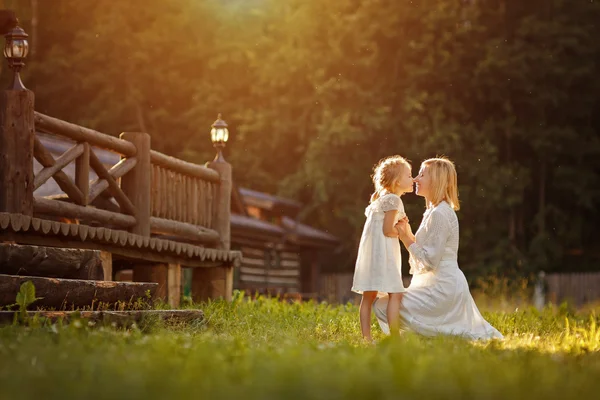 Linda mãe loira em vestido branco gentilmente abraça uma menina kneeli — Fotografia de Stock