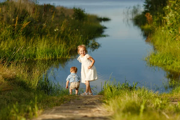 Hermano pequeño y hermana jugando en la hierba en un fondo o — Foto de Stock