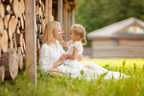 Мама блондинка в белом платье играет с дочерью на коленях — стоковое фото