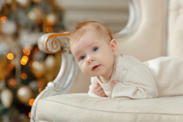 Niña bebé acostado en una silla en el fondo de la Navidad — Foto de Stock