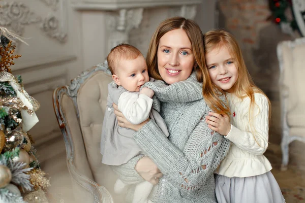 Bela mãe feliz com filhas pequenas sentadas nas costas — Fotografia de Stock