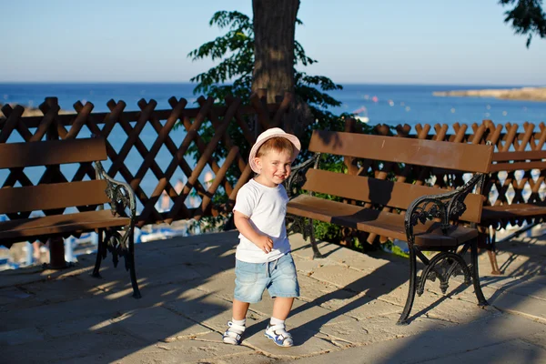 Encantador niño con sombrero corriendo sobre el fondo de palmeras en s —  Fotos de Stock