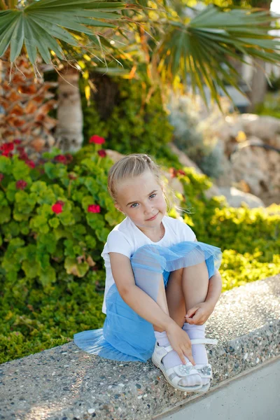 Krásná blondýnka 5 let stará v modré sukni na pozadí — Stock fotografie