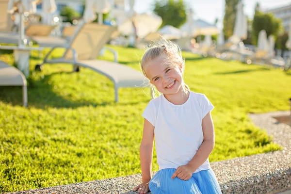 Mooi blond meisje 5 jaar oud in een blauwe rok glimlachend op de — Stockfoto