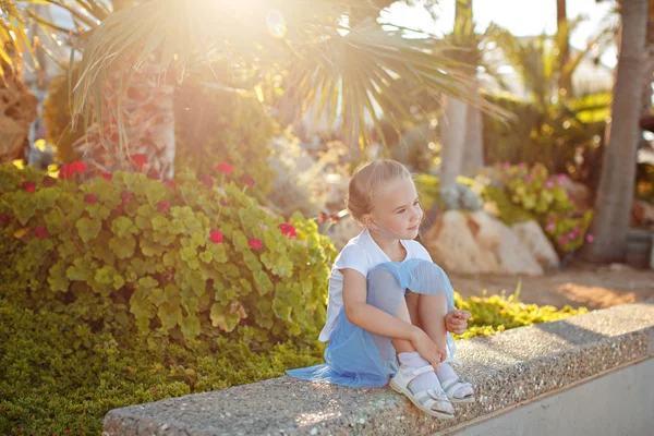 Hermosa chica rubia de 5 años en una falda azul sonriendo en el —  Fotos de Stock