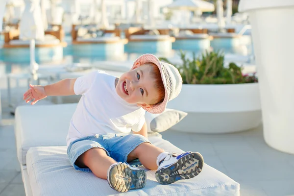 Kleiner kleiner Junge mit Hut sitzt auf dem Hintergrund des Pools und — Stockfoto