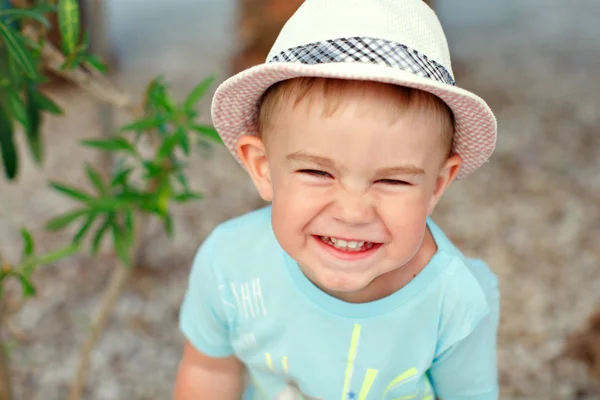 Niño encantador con sombrero y camisa azul, de pie junto a la palma de la mano —  Fotos de Stock