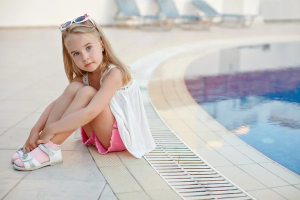 Urocza blond dziewczyna w różowe szorty siedzi wokół basenu w th — Zdjęcie stockowe