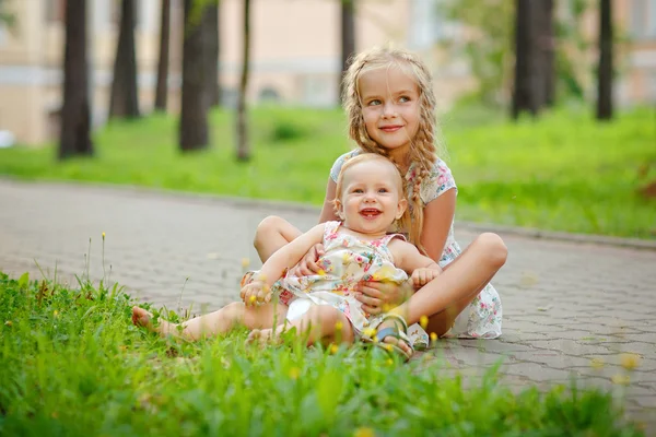 Două surori fermecătoare blondă fată îmbrățișare și râzând pe the gra — Fotografie, imagine de stoc