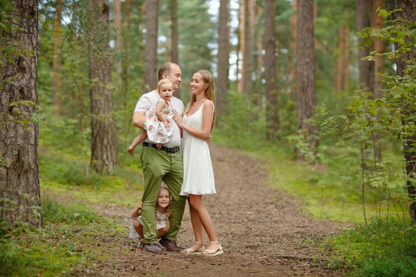 Family - mother, father and two daughters blonde walking through — Stock Photo, Image