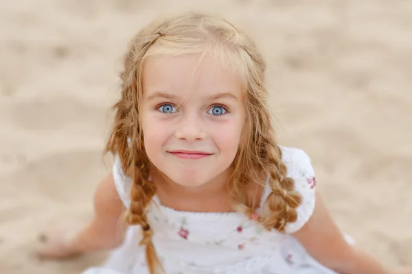 Portret lachwekkend blond meisje met pigtails en blauwe ronde ogen — Stockfoto