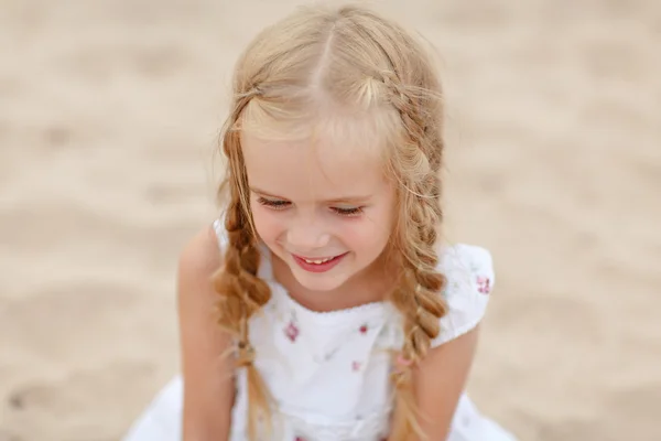 Stående SKRATTLYSTEN blond flicka med flätor och blå runda ögon — Stockfoto