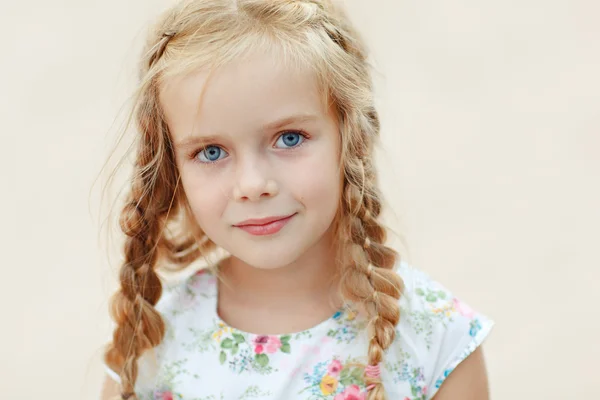 Portret lachwekkend blond meisje met pigtails en blauwe ronde ogen — Stockfoto