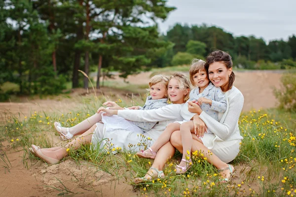 Mamma och hennes tre döttrar kramar i en skog på sommaren — Stockfoto