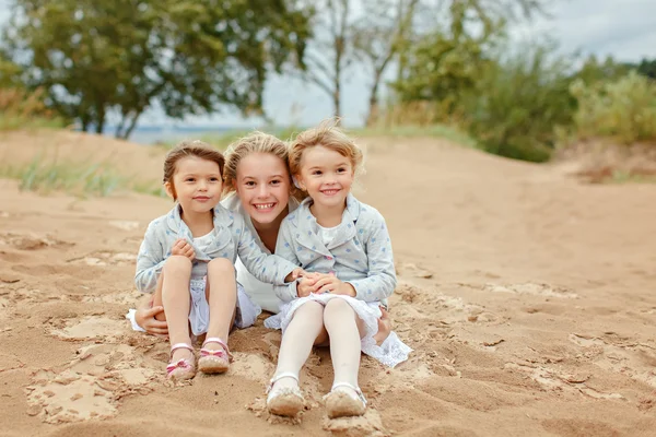 Three little girls are adorable sisters hugging on the backgroun — Stock Photo, Image