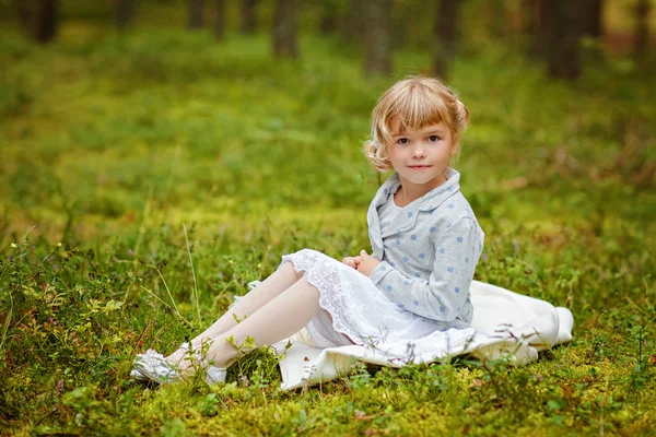 Charmig Baby flicka med bruna ögon sitter på gräset i — Stockfoto