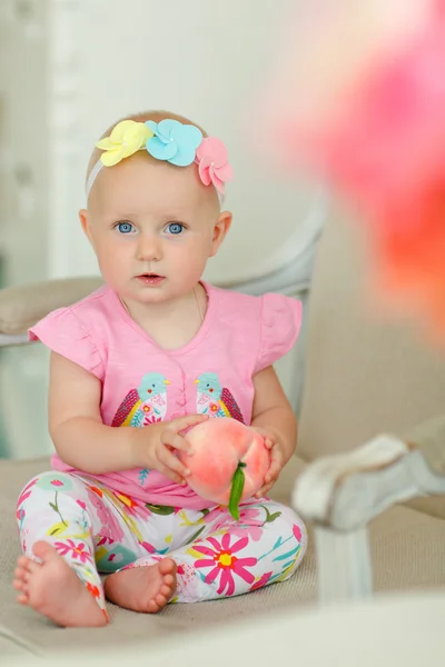 Pequena menina bonita com grandes olhos azuis, sentado em um chai — Fotografia de Stock