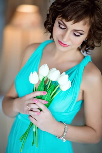 Atrakcyjny dziewczynka w niebieską sukienkę z tulipany w rękach — Zdjęcie stockowe