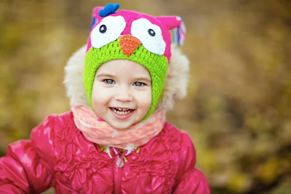 Smilende lille pige i en rød jakke og hat med ugle - Stock-foto