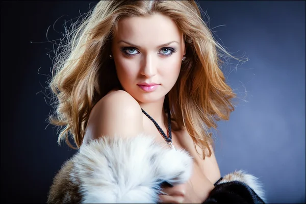 Sinnliche sexy Mädchen Blondine in einem Pelzmantel auf blauem Hintergrund, Nahaufnahme — Stockfoto