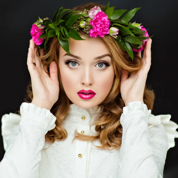 Retrato de una hermosa chica glamorosa de pelo amarillo sensual en una blusa blanca con una corona de flores en la cabeza, en el estudio sobre un fondo oscuro, de cerca — Foto de Stock