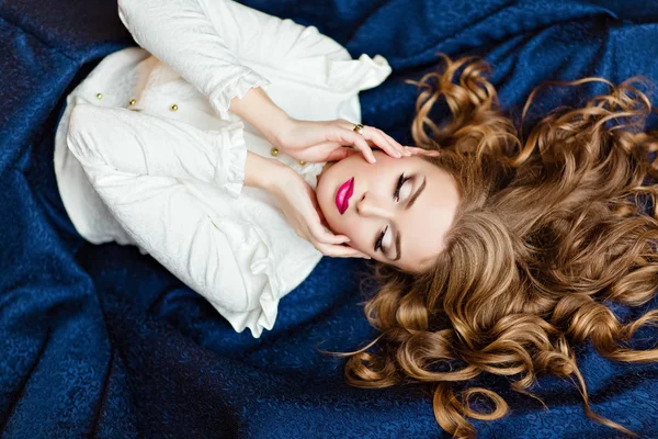 Портрет очень красивой чувственной гламурной рыжеволосой девушки в белой блузке и голубой юбке, лежащей на полу в Студии на темном фоне с закрытыми глазами — стоковое фото