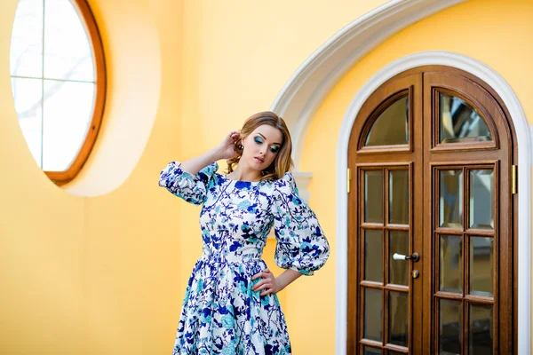 Porträt eines sehr schönen Mädchens mit blauem Kleid auf Tür- und Fensterhintergrund — Stockfoto