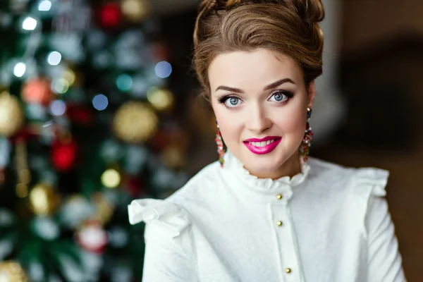 Портрет очень красивой улыбающейся блондинки в белой блузке на фоне рождественских огней — стоковое фото