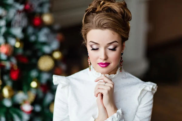 Portré a szép szőke lány egy fehér blúz, a szeme zárva tart, a háttérben a karácsonyi fények — Stock Fotó