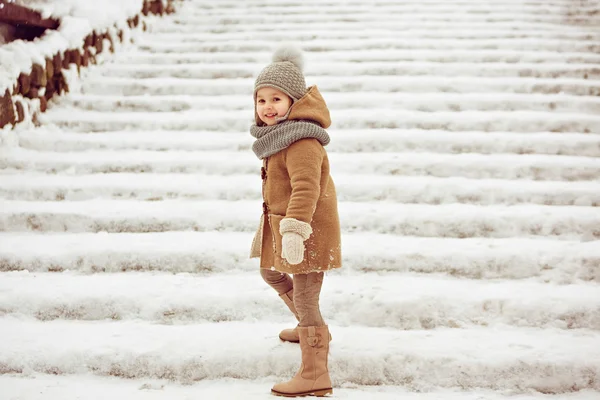 Zeer mooi mooi meisje kind in een beige vacht en een grijze hoed gaan — Stockfoto