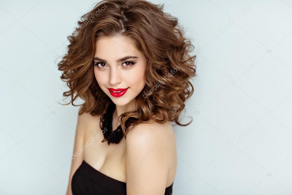 Portrait of a beautiful glamorous brunette with curly hair and b