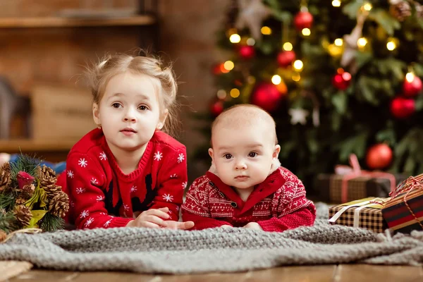 Mały chłopiec dziecko w czerwonym swetrze i jego starsza siostra leżąc — Zdjęcie stockowe