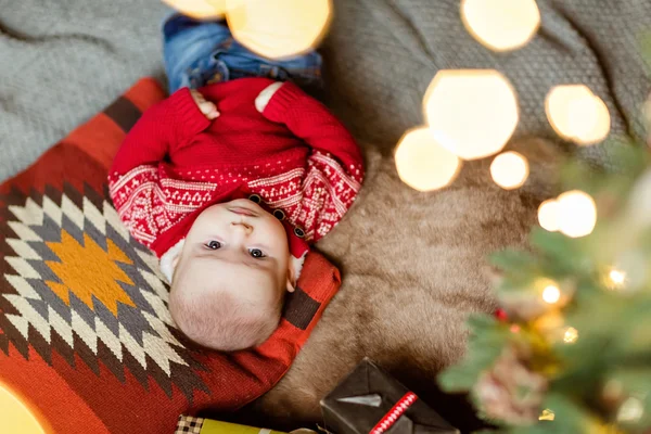Очаровательный малыш красный свитер лежит на полу на подушках — стоковое фото