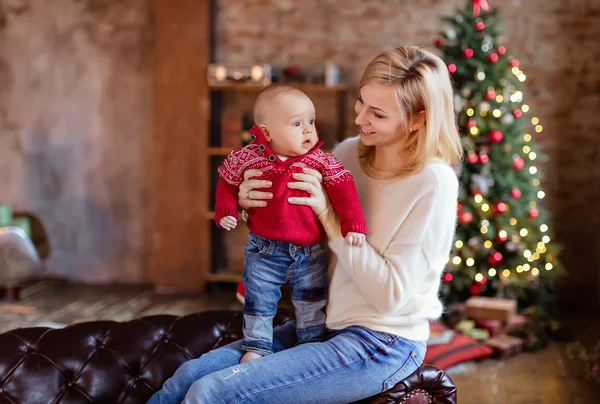 Charmante Mutter Blondine im weißen Pullover sieht seine kleine — Stockfoto