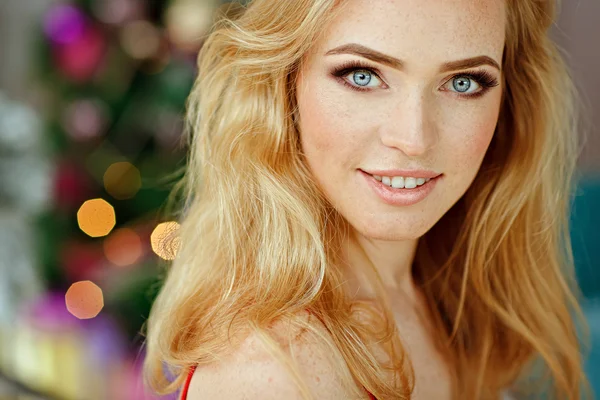 Portrait of sensual blond girl with freckles, against a background of Christmas trees and lights in the interior, close-up — Stock Photo, Image