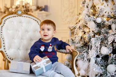 Mavi kazaklı küçük sevimli bebek oğlan oturuyor bir sandalyeye bir