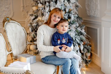 Annem beyaz kazaklı gülümsüyor ve büyüleyici bir erkek bebek tutan ben