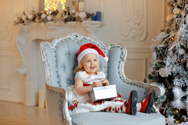 Niña encantadora rubia en un sombrero de santa rojo, sonriente y — Foto de Stock