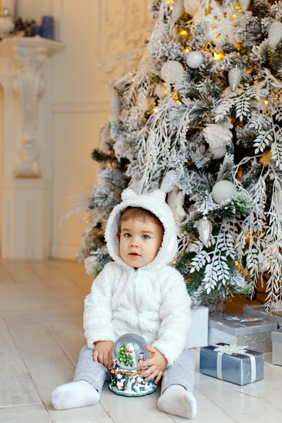 Pequeno menino encantador roupa polar urso filhote senta-se perto de um Chri — Fotografia de Stock